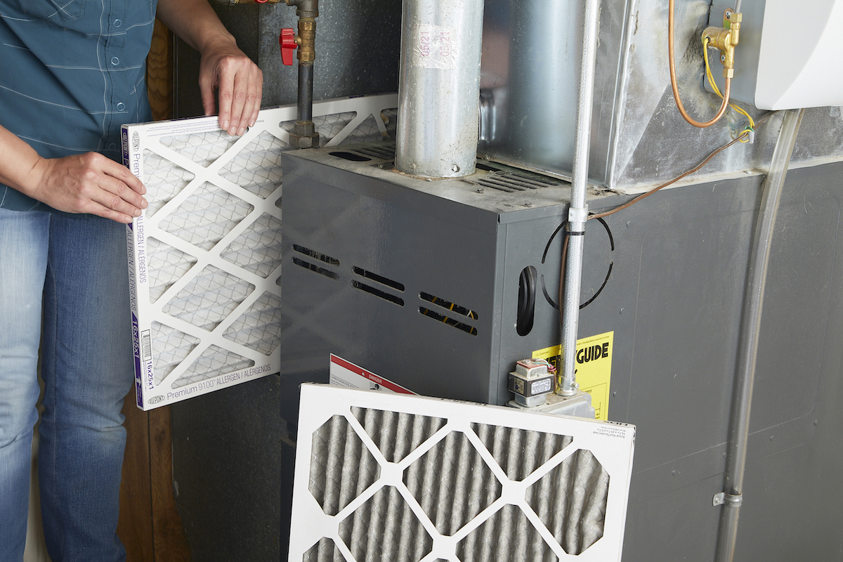 Woman replaces filter in furnace with a new one.