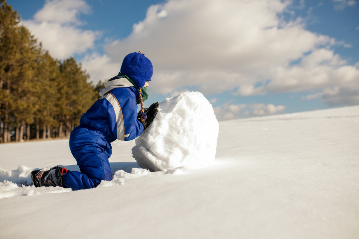 how to build a snowman - boy pushing snowball