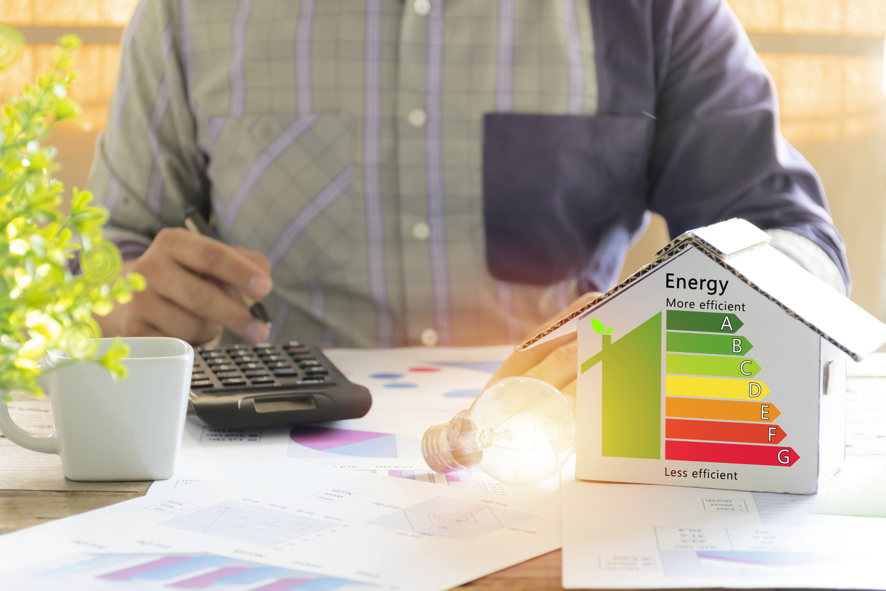 Man at his desk, reducing energy costs—model of home on desk next to him.