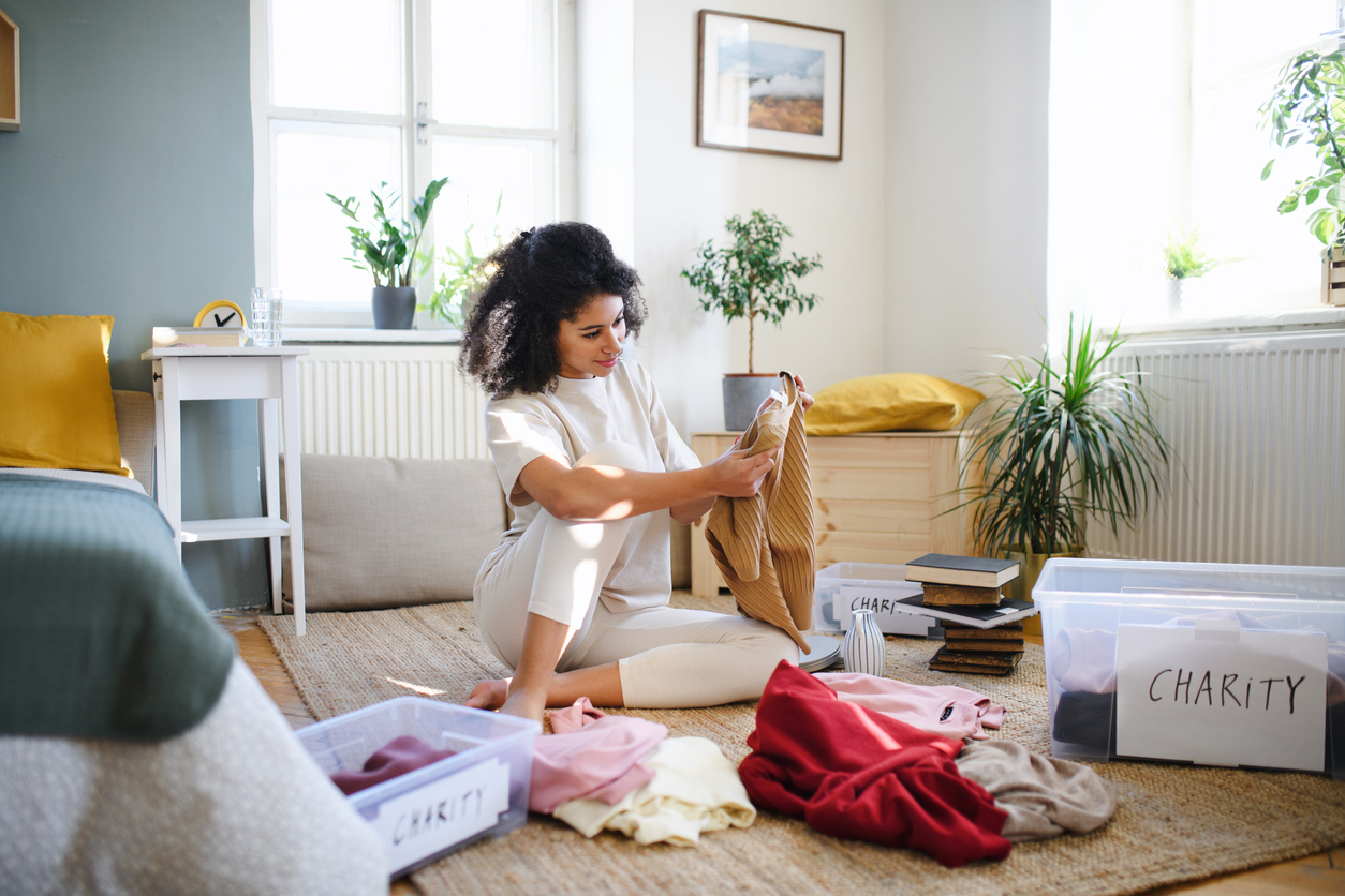 Woman Sorting Wardrobe into keep and charity piles.