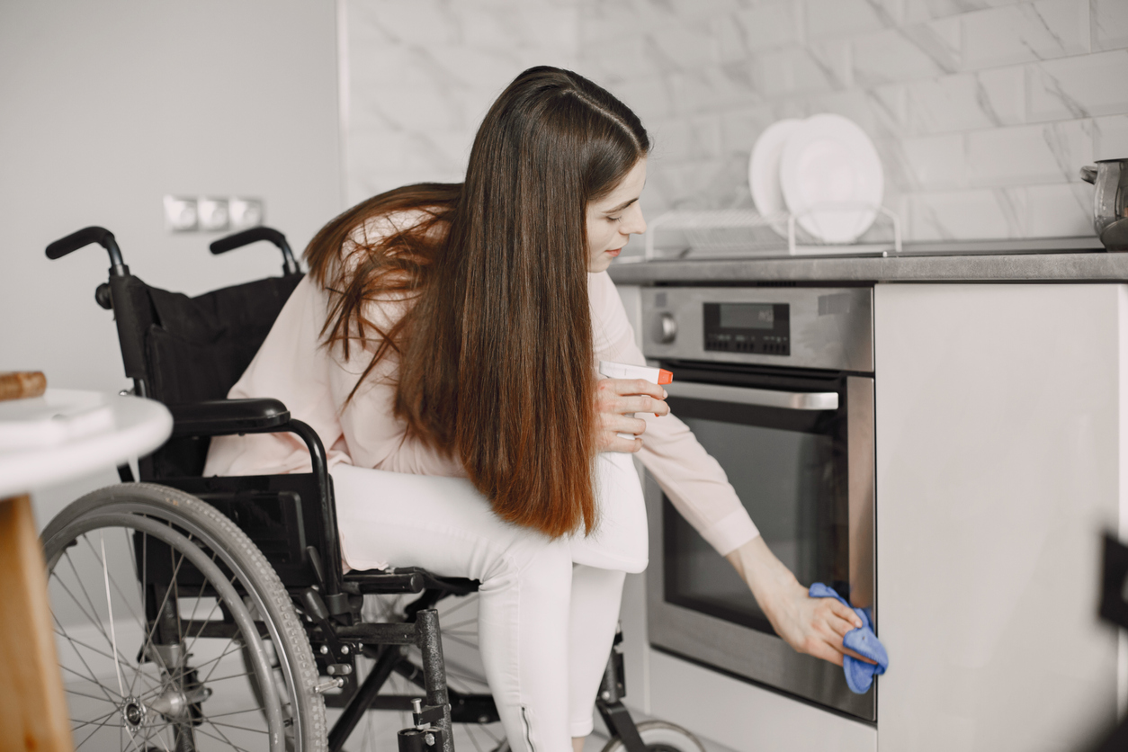 iStock-1353927107 cleaning resolutions woman in wheelchair cleaning oven surface.jpg