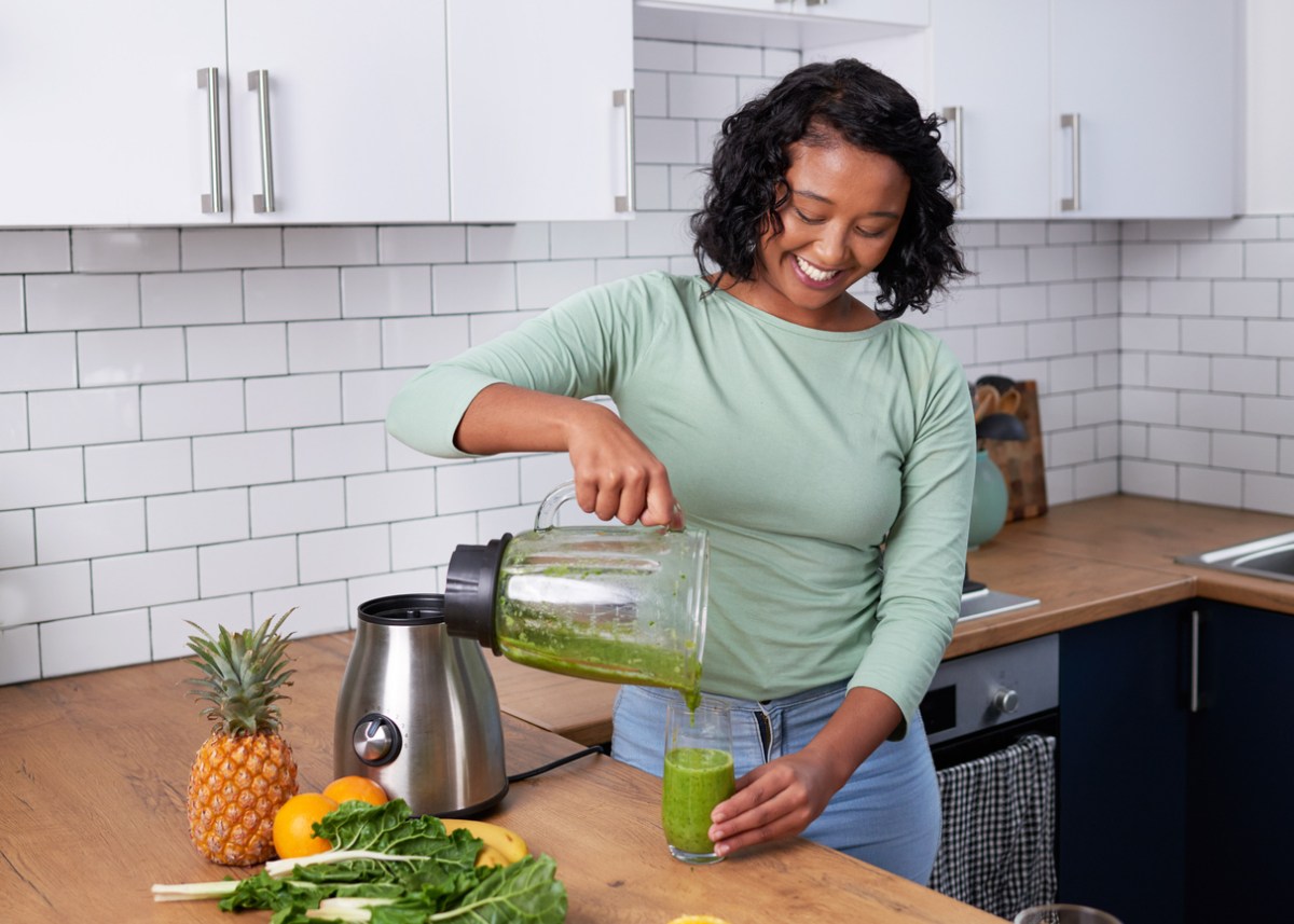 iStock-1419300138 how to clean a blender A young multi-ethnic woman pours a fresh green smoothie from blender in kitchen stock photo.jpg