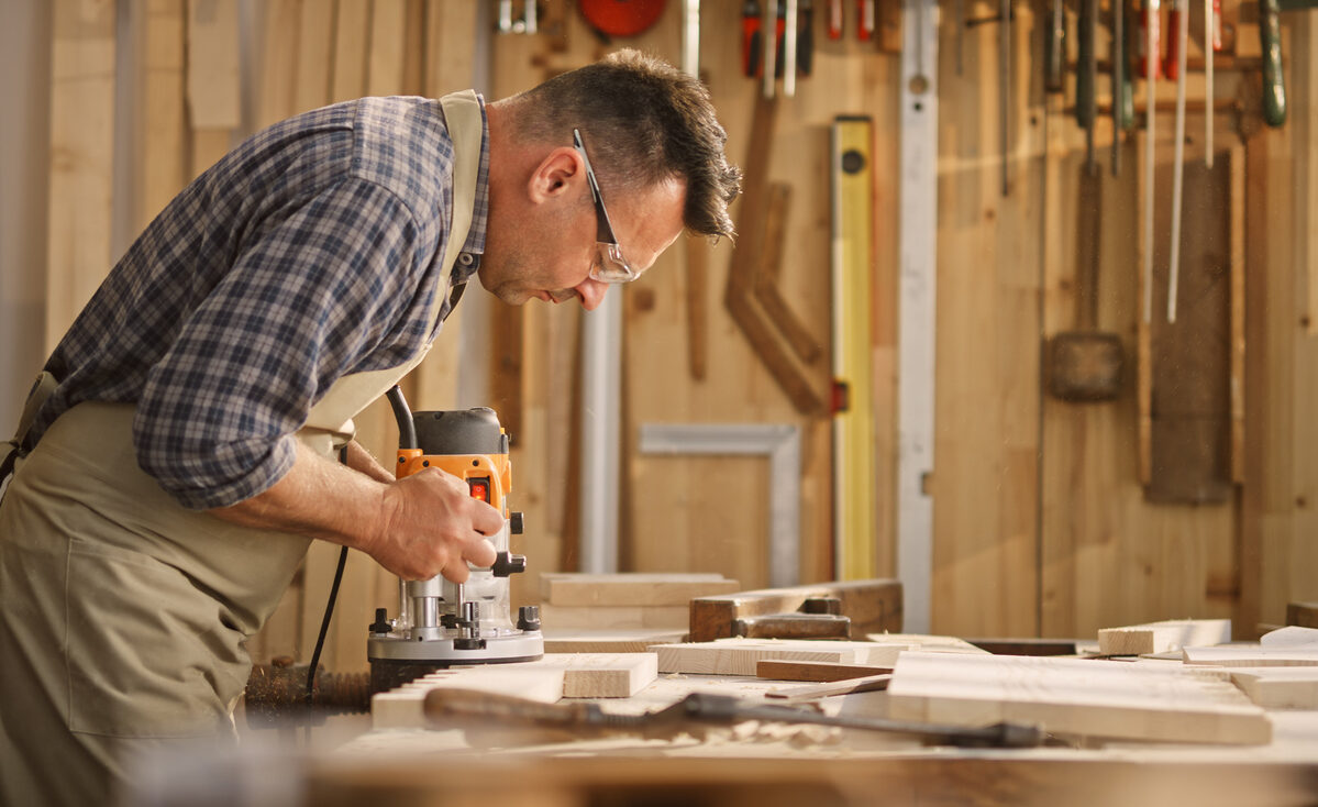 Man in his workshop using a woodworking router.