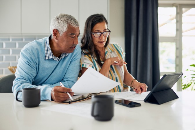 Mature couple look over tax statements over coffee at kitchen island.