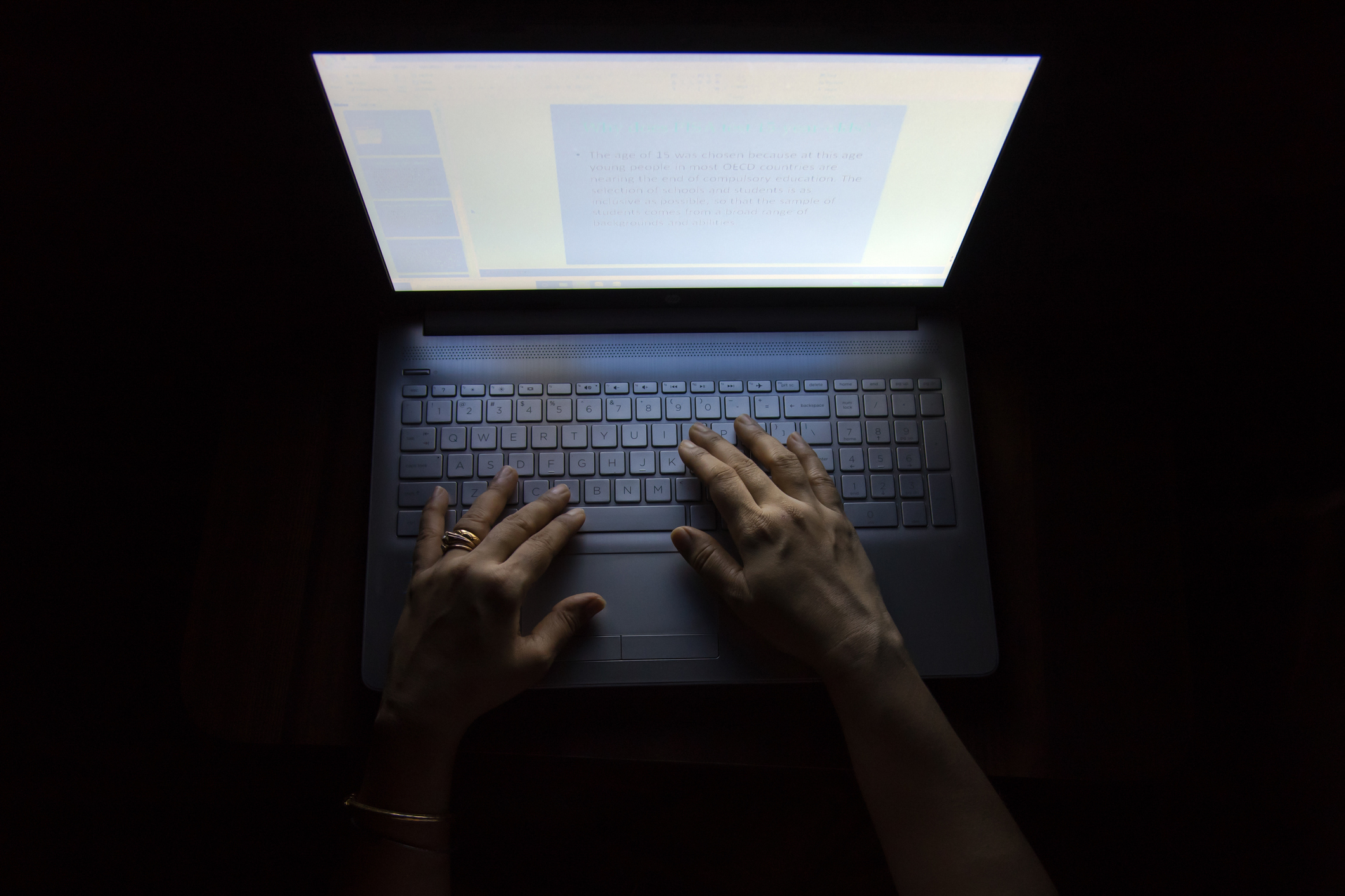 Female hands on a computer, working in the dark