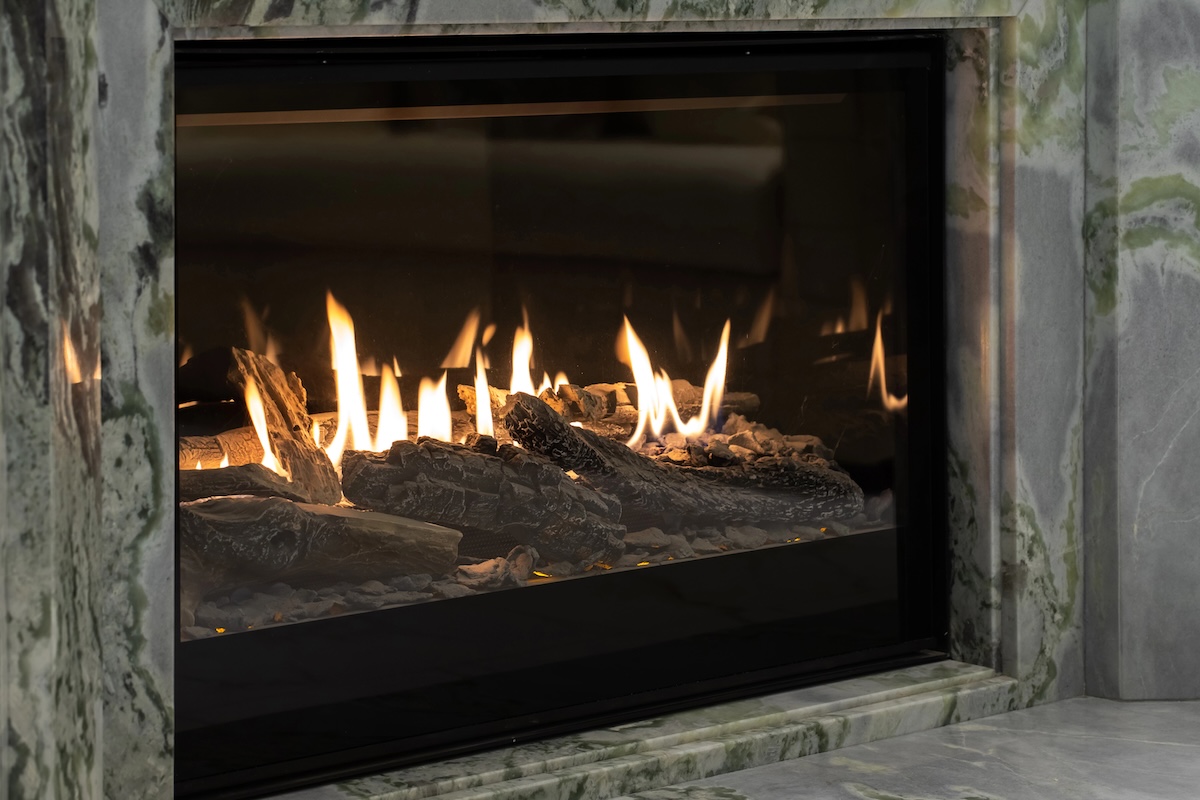 Gas fireplace with realistic-looking logs framed in a grey marble surround.