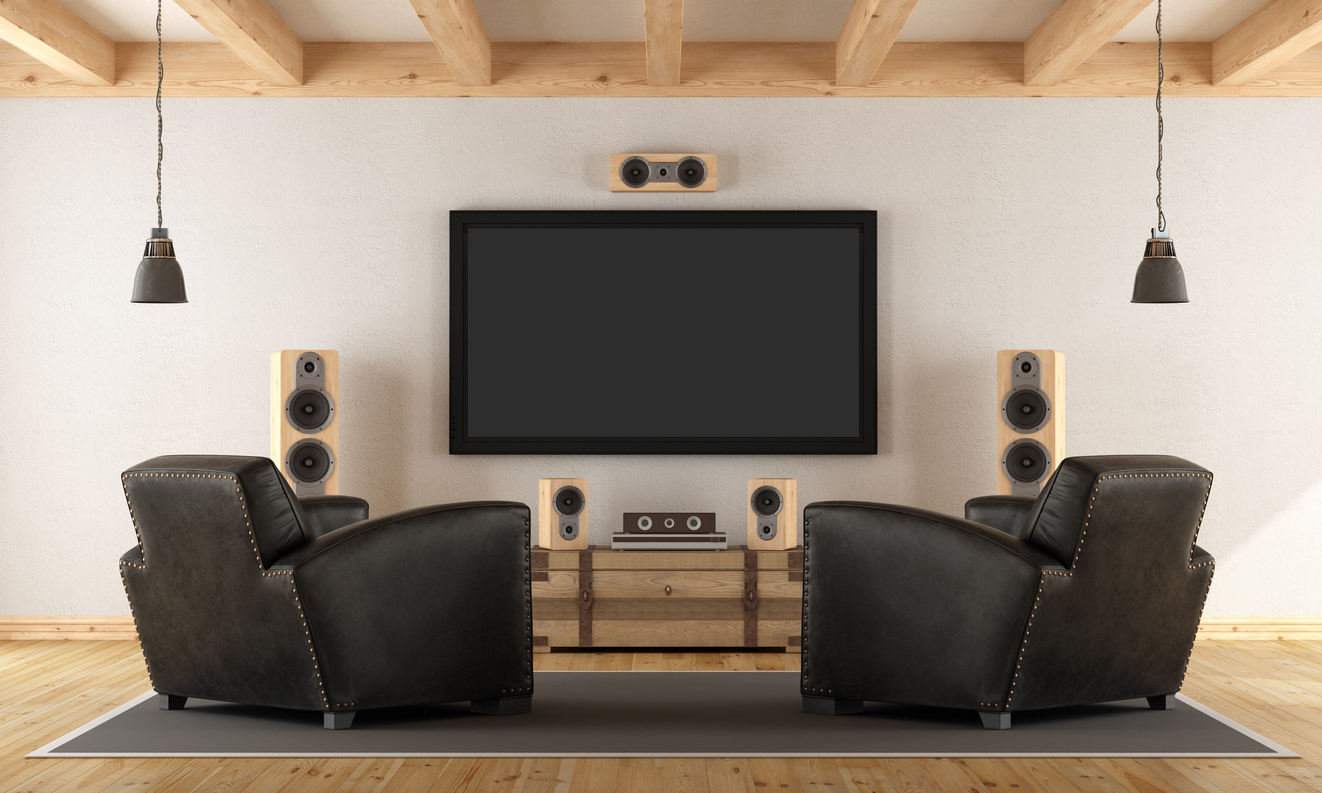 leather armchairs facing a mounted TV and home theater speakers