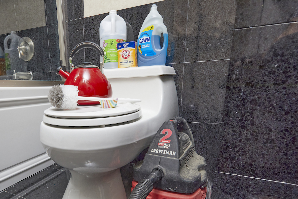 Materials used to unclog a toilet without a plunger, including a shop vac, tea kettle, dish soap, and more.