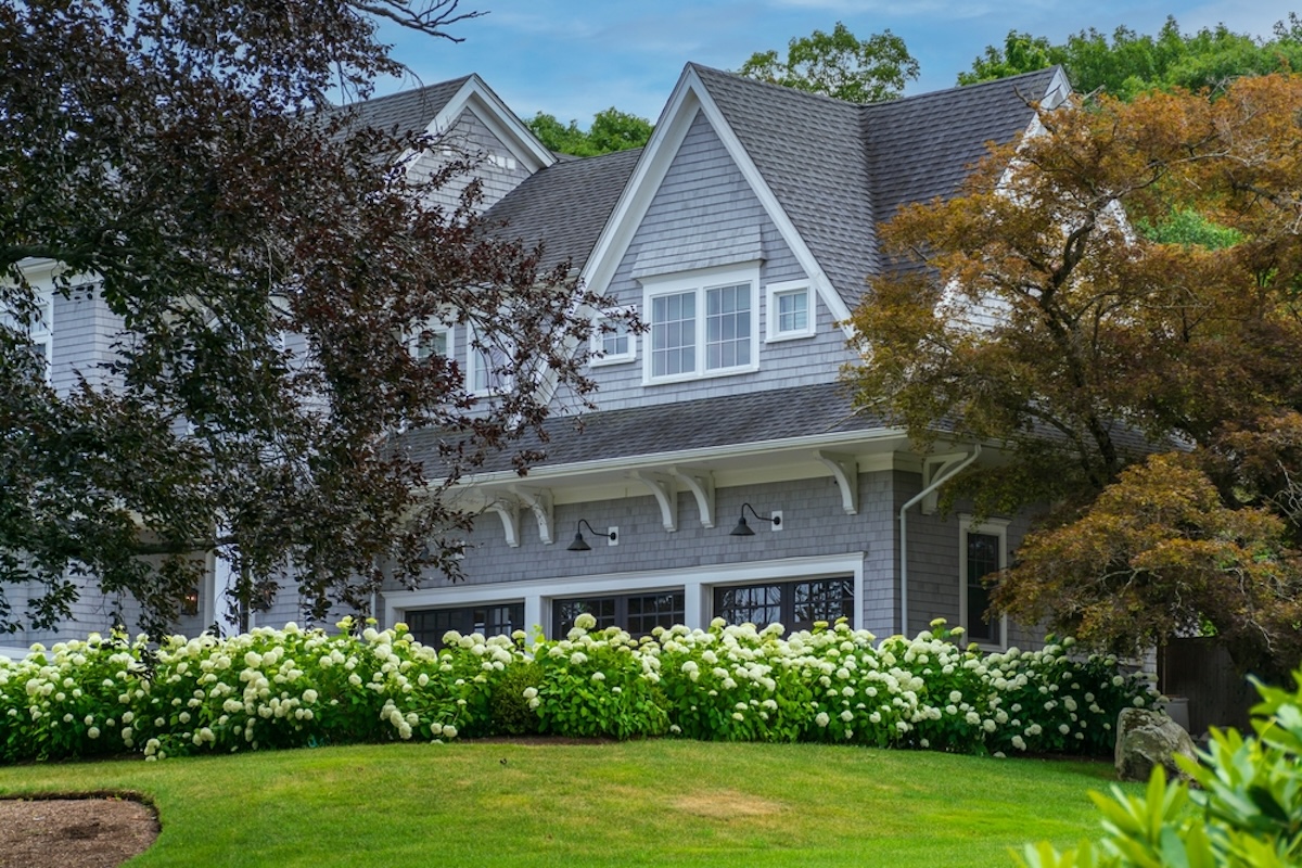 A large two-story home with yellow hydrangea shrubs planted in front.