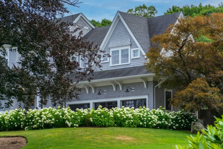 A large two-story home with yellow hydrangea shrubs planted in front.