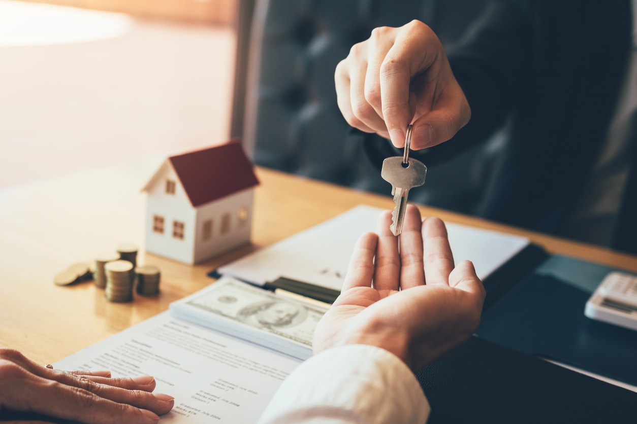 iStock-1131335531 why not to own a house in your name handing keys to a house to someone