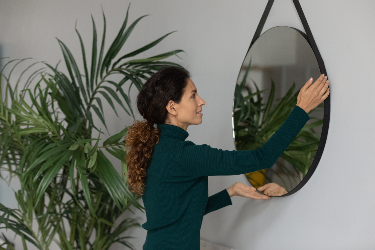 iStock-1297735499 Home Depot shopping woman hanging up mirror in house