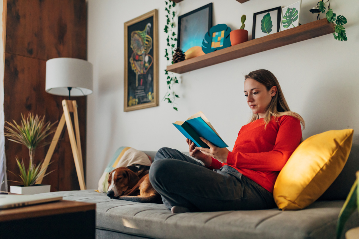 iStock-1324677620 how to improve your life woman reading in cozy nook at home with dog