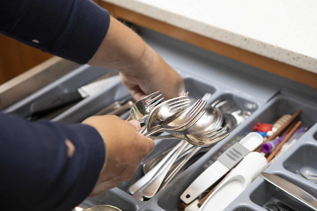 iStock-1329464289 procrastination hacks Close-up of a woman's hands putting forks and spoons into a cutlery drawer