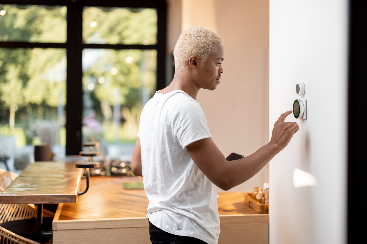 The 11 Biggest Mistakes You Can Make With Your Smart Home young man using smart thermostat