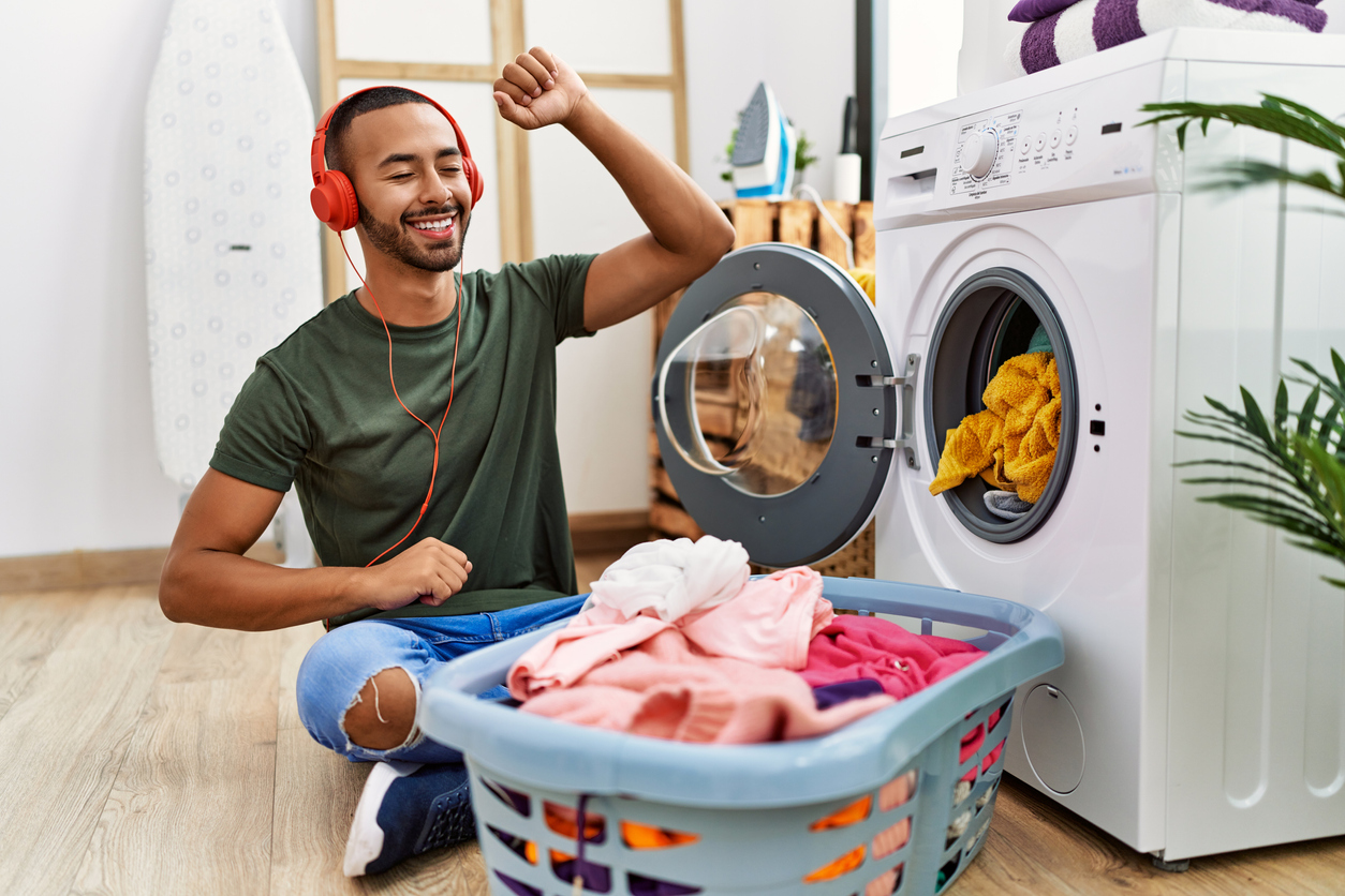 iStock-1351843702 productivity hacks young man listening to music and doing laundry