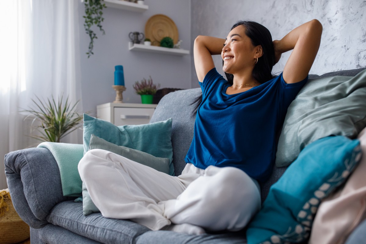 iStock-1353365157 ways to improve your life happy woman on couch daydreaming