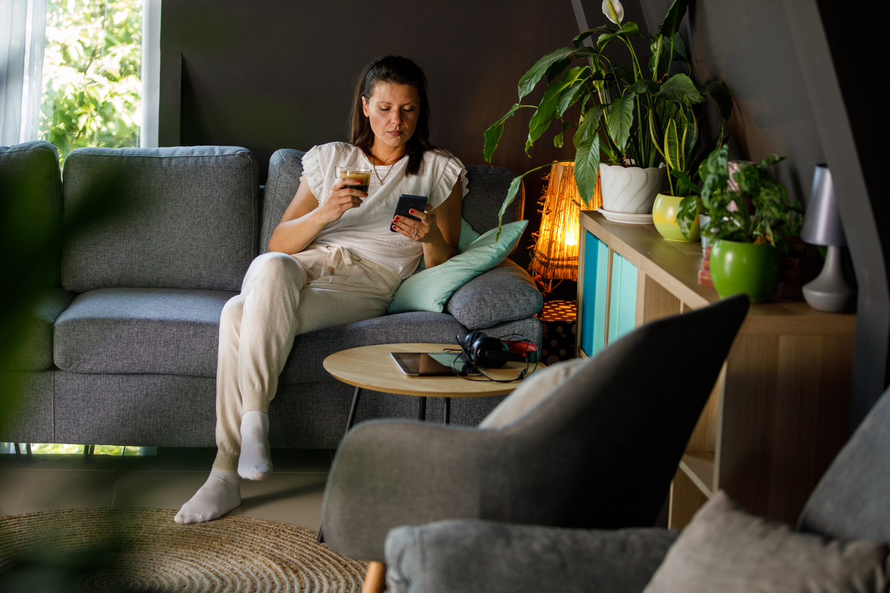 what is a den woman on couch relaxing in cozy atmosphere looking at phone