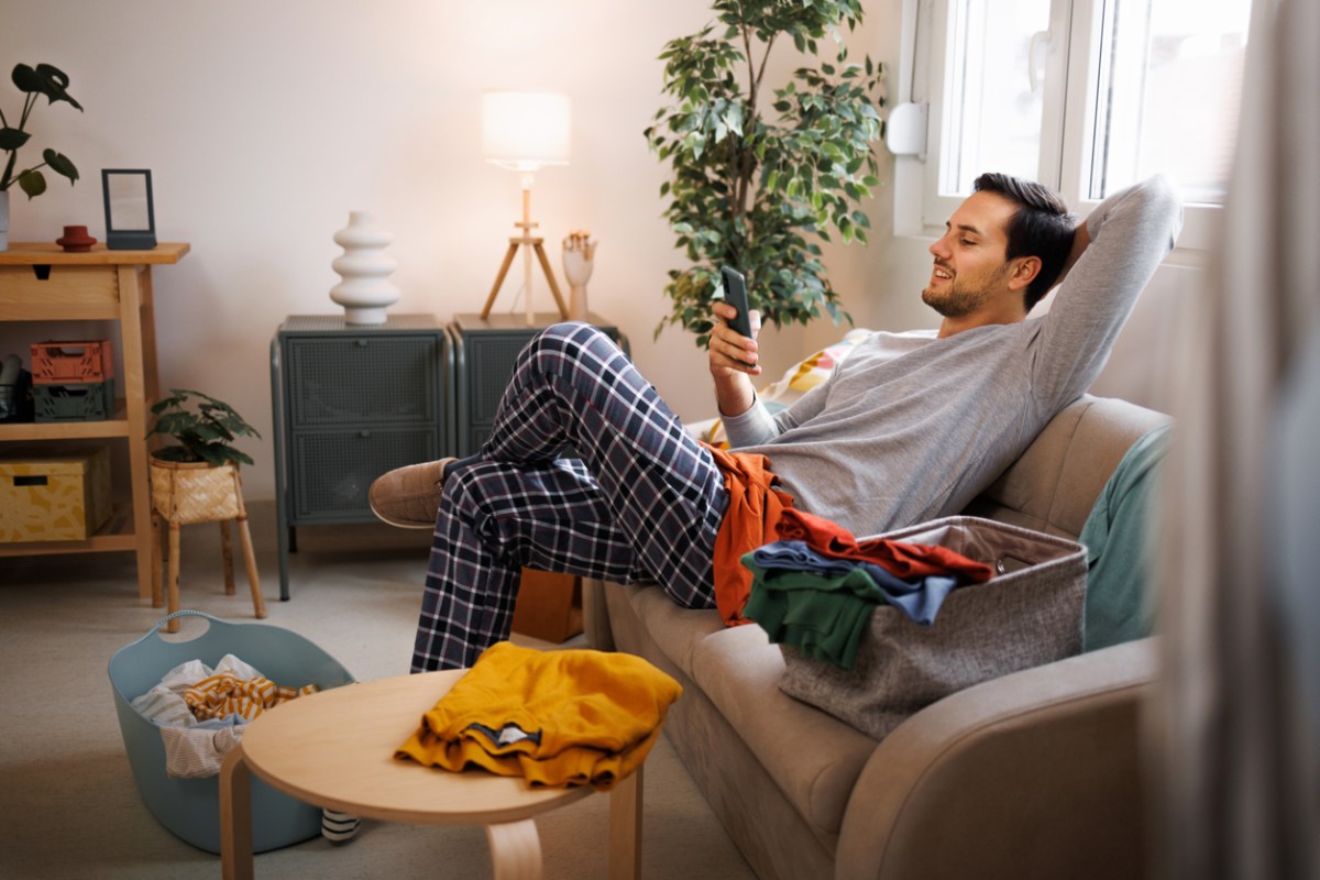iStock-1435987105 procrastination hacks man relaxing instead of doing housework