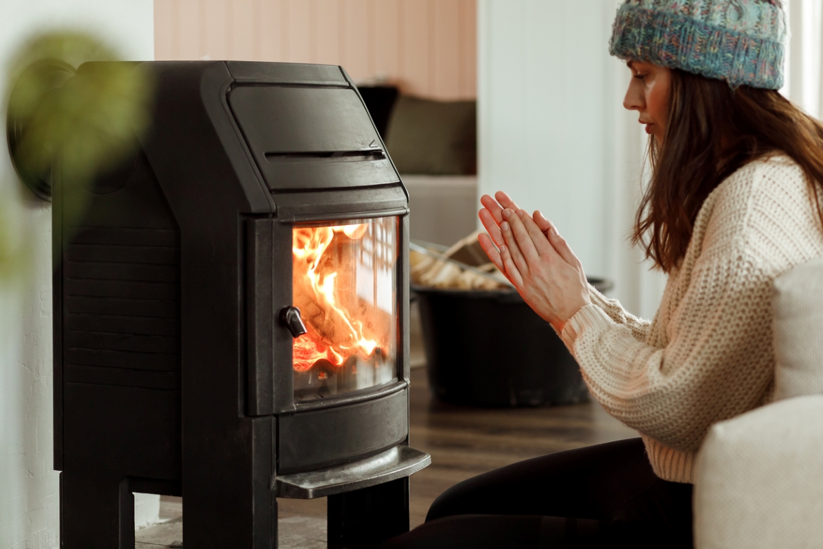 gas vs. electric fireplace - woman warming by fireplace
