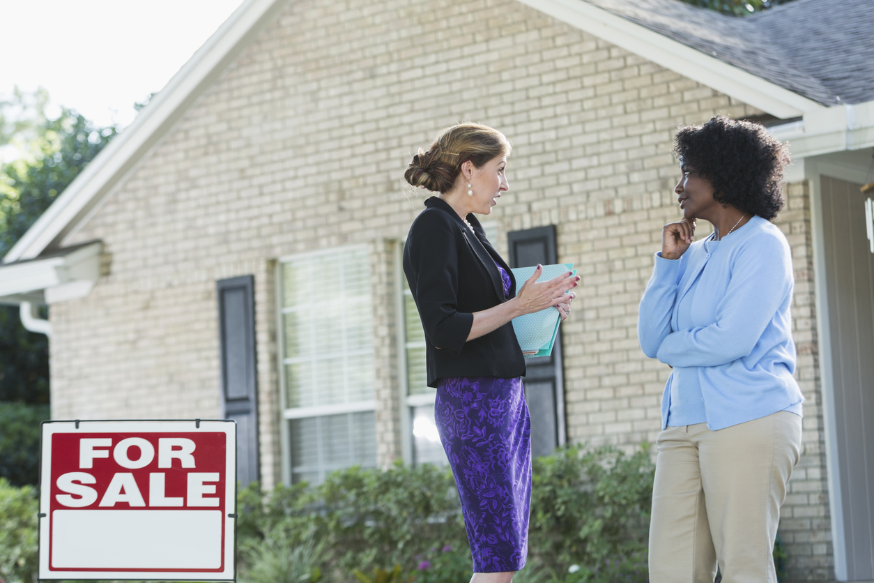 iStock-509182770 inheriting a house real estate agent talking to woman outside a house with a for sale sign