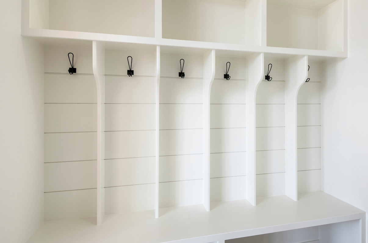 White mudroom shelves and cubbies with black hanging hooks. 
