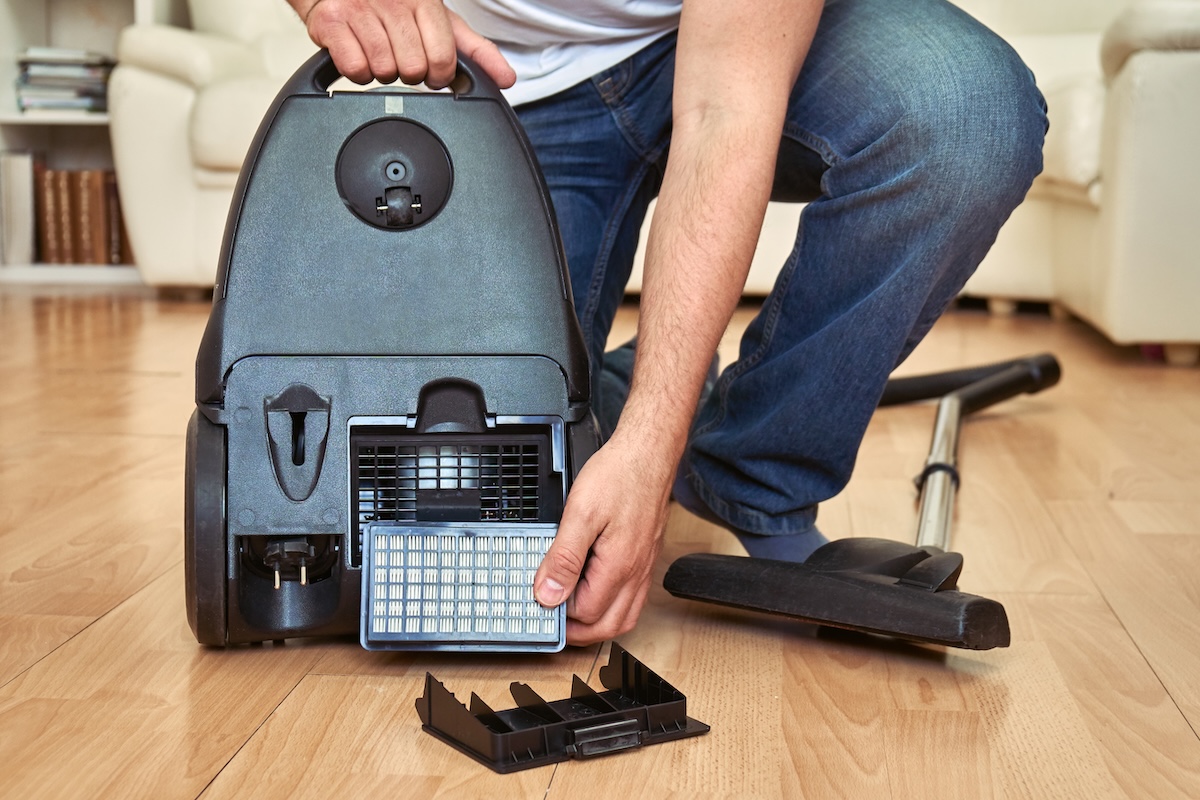Man replacing a HEPA filter in vacuum cleaner at home.