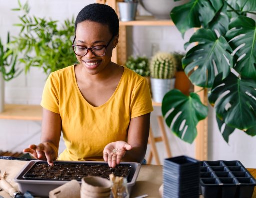 African-American young woman placing seeds in a seed-starting tray.