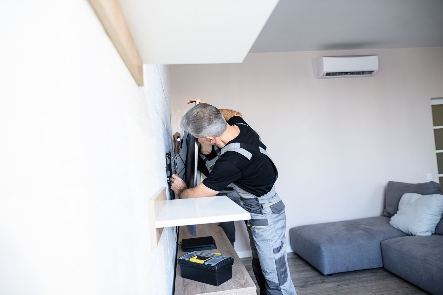 A handyman installs a TV mount. 