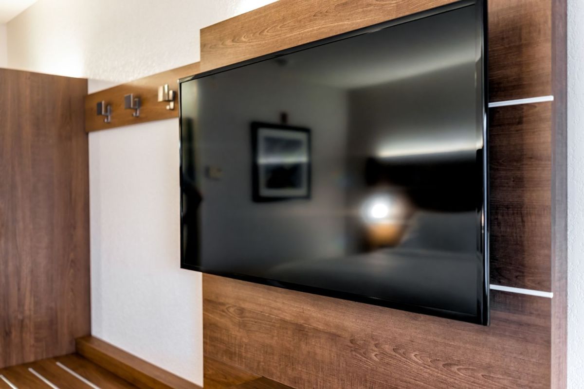 A TV hangs on a wood panel wall.