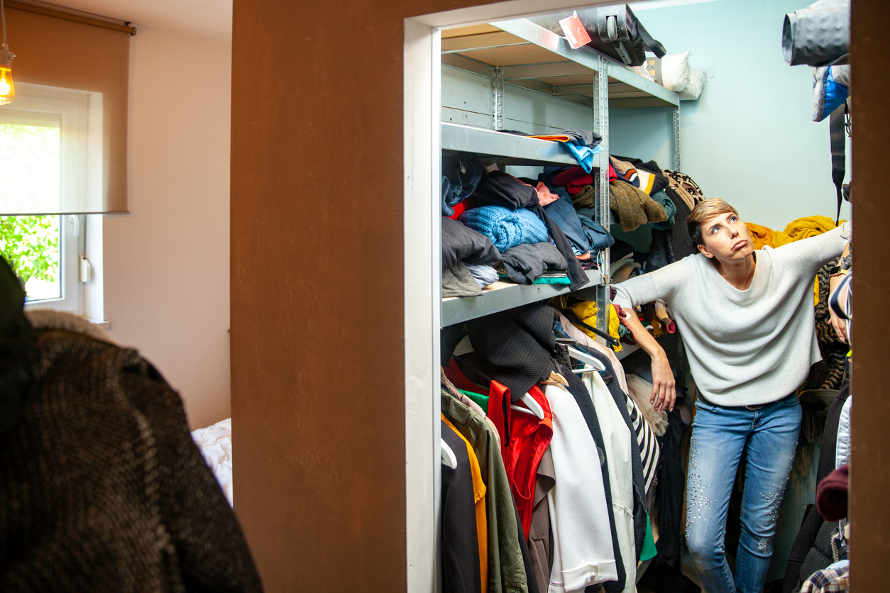 iStock-1154563866 walk-in closet storage space woman looking at crowded closet