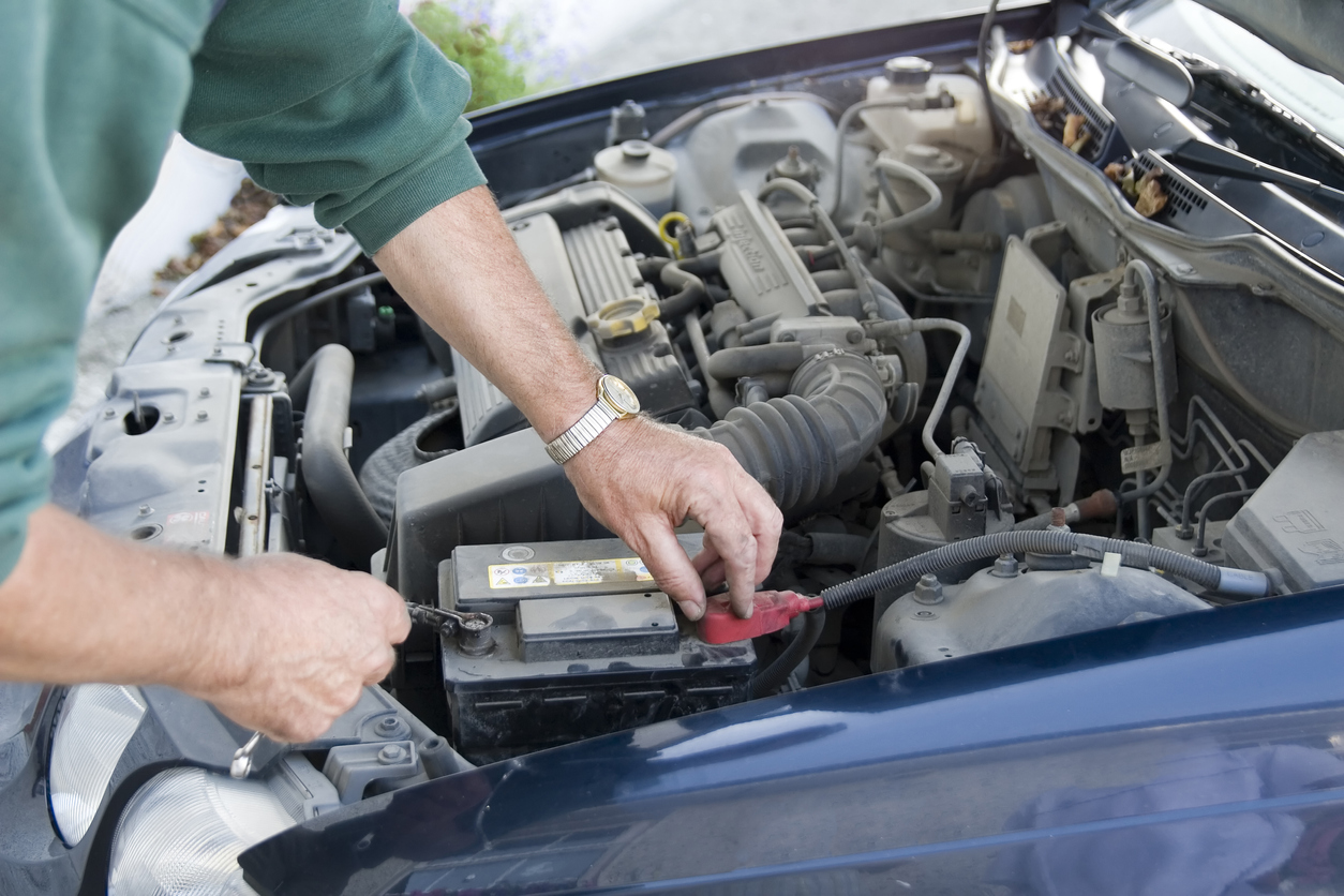 how to clean car battery terminals man inspecting car battery in open engine