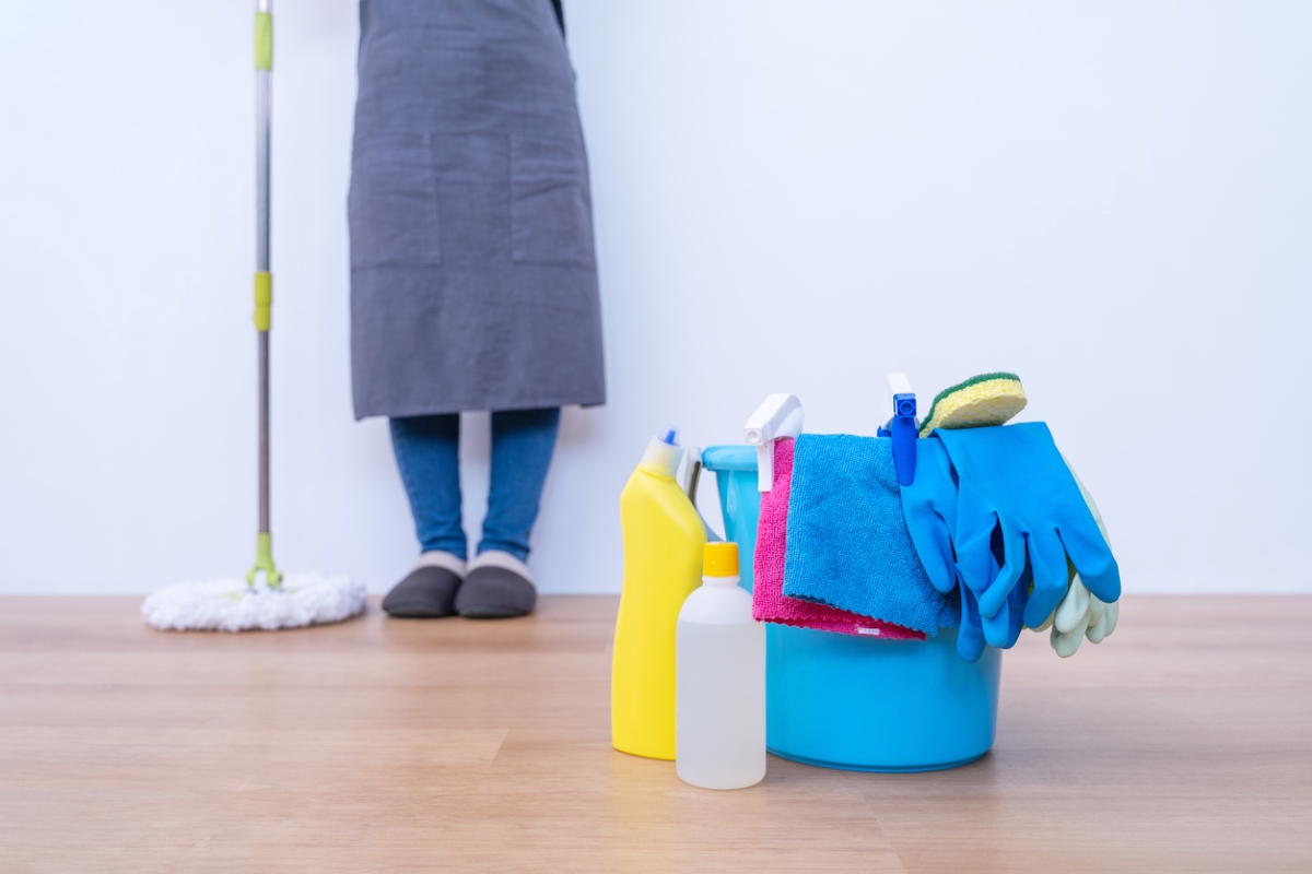 ways to clean behind and under every appliance - person standing with cleaning supplies