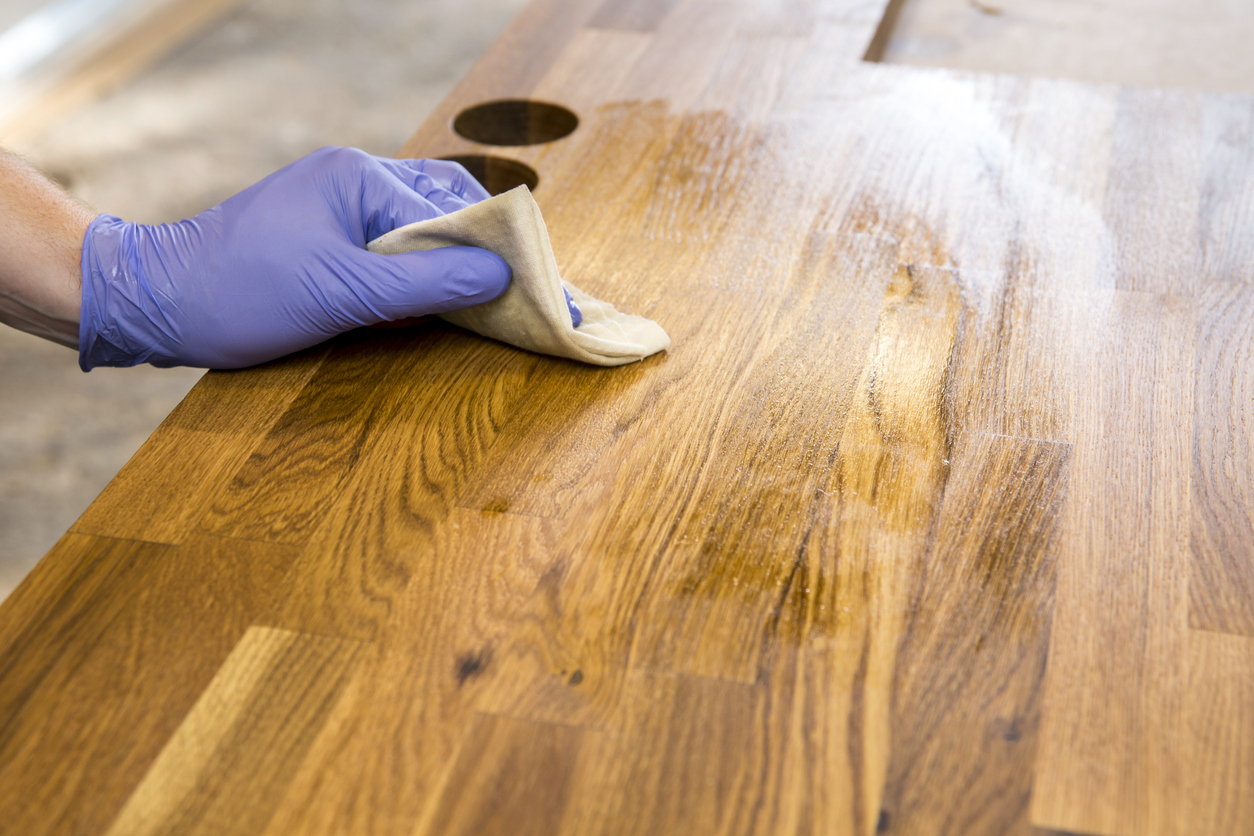 coconut oil uses hand wiping wood surface with oil cloth wearing purple glove