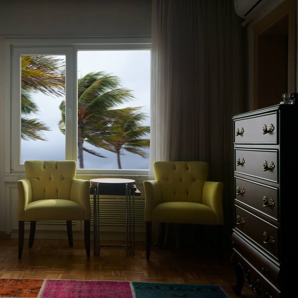 security window film hurricane concept dark living room with window overlooking strong wind palm trees