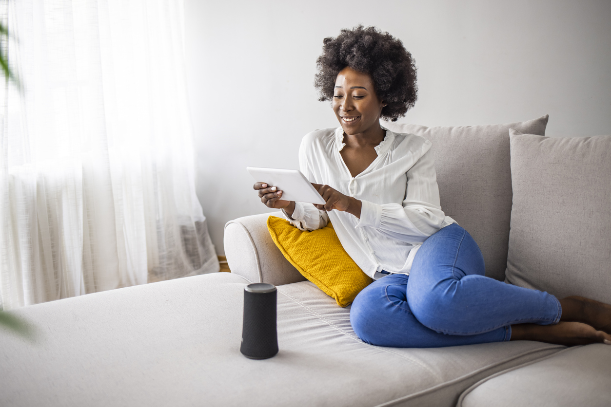 iStock-1321422469 tax refunds home improvement Happy young woman controlling smart home devices with a voice commands and smart speaker at home