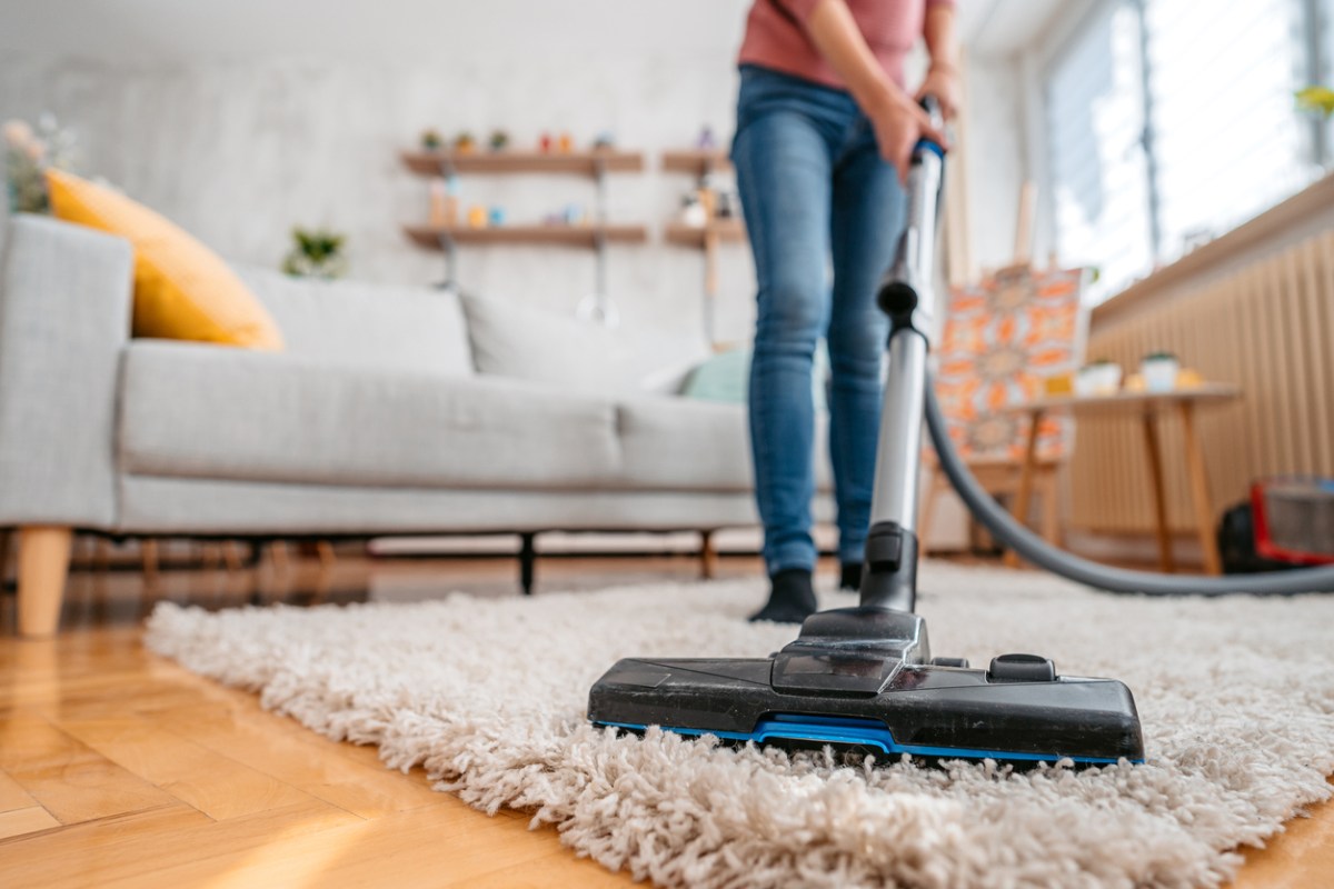 9 things you should never vacuum woman vacuuming shaggy rug in living room
