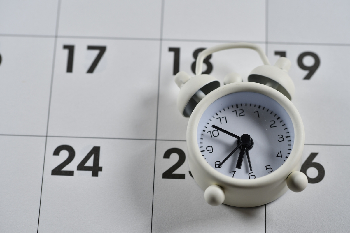 daylight savings time 2023 - clock laying on paper calendar