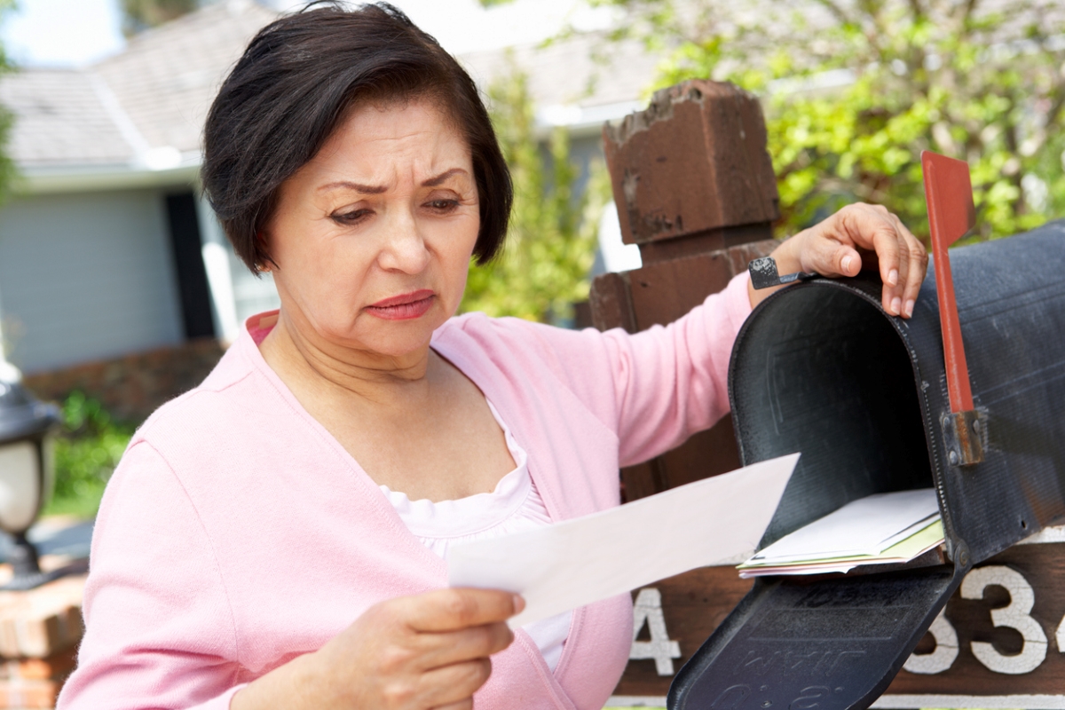 home title theft - older woman frowning at mail