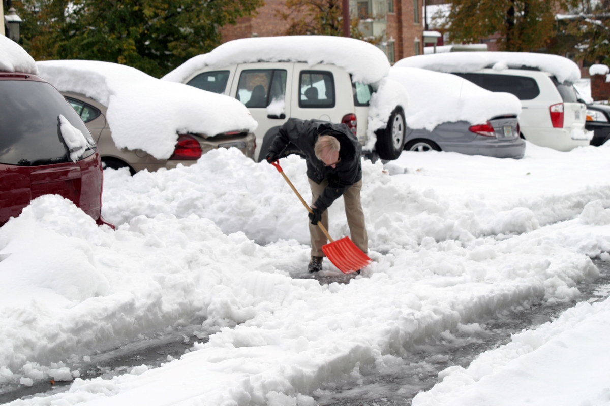 farmers almanac winter forecast - man shoveling snow near buried cars