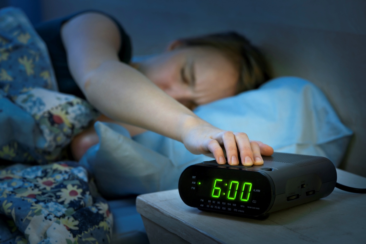 daylight savings time 2023 - woman turning off alarm