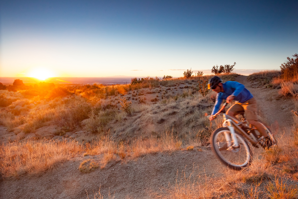 iStock-495751190 cheapest places to buy land man riding bike during sunset near albequrque new mexico