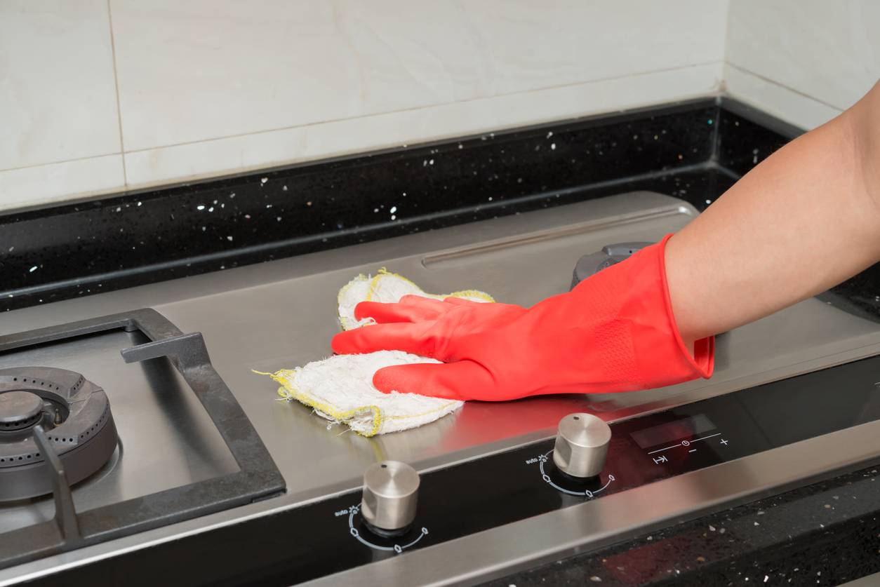 coconut oil uses wiping stainless steel stovetop with rag wearing red gloves