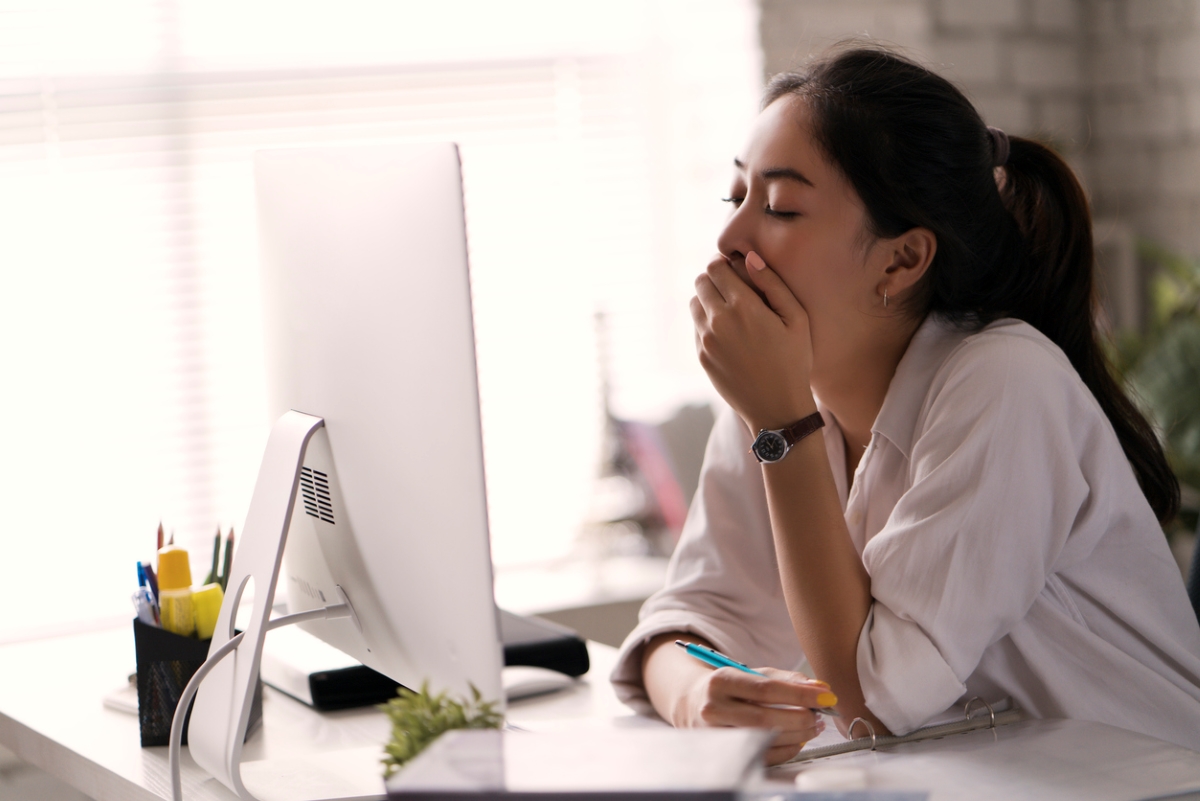 daylight savings time 2023 - woman yawning in front of computer