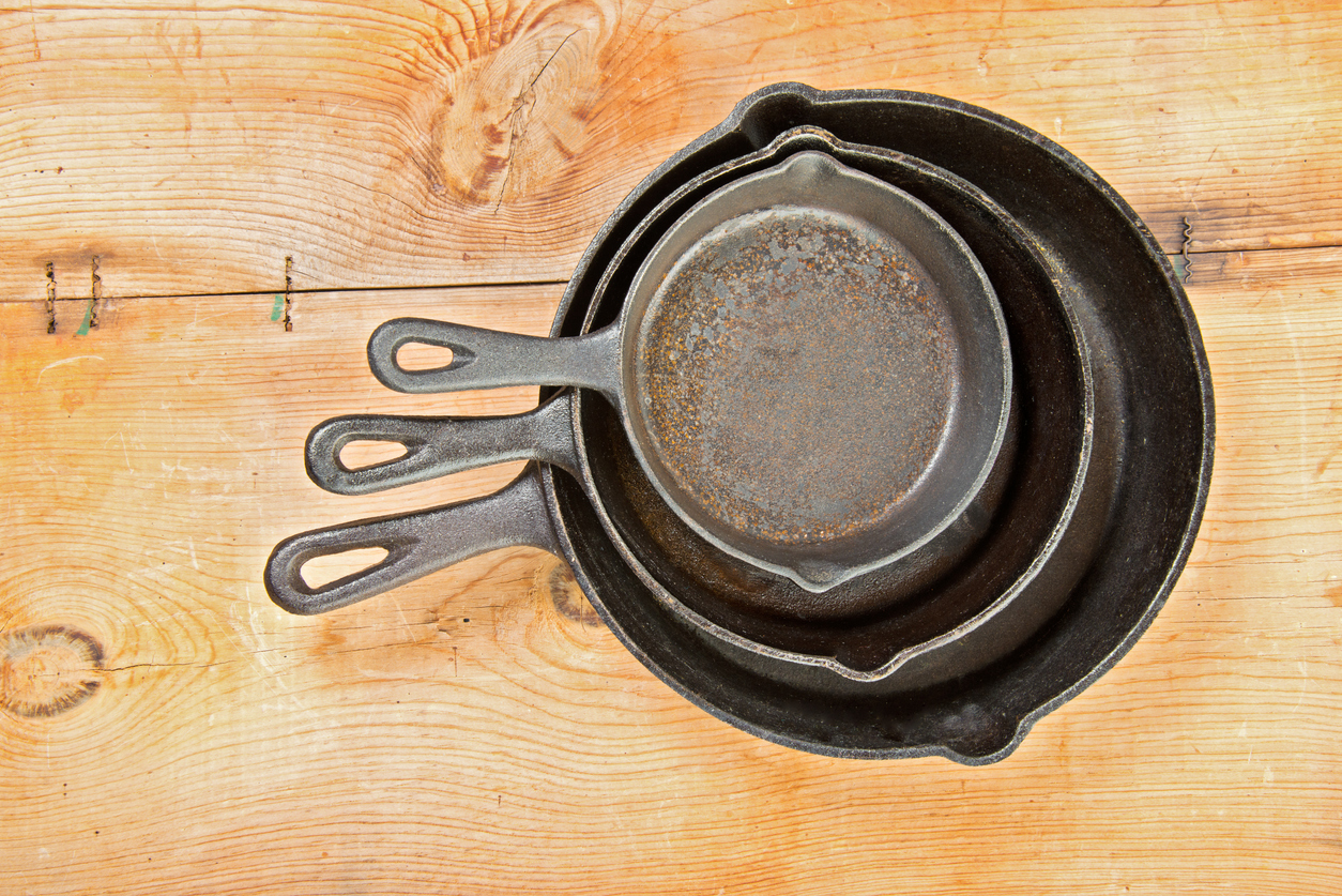 three old cast iron frying pans with rust