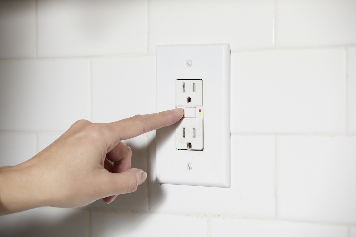 Person pushes reset button on GFCI outlet.