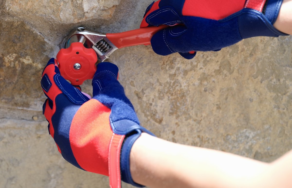 Plumber fixes leaking pipe and faucet outside.