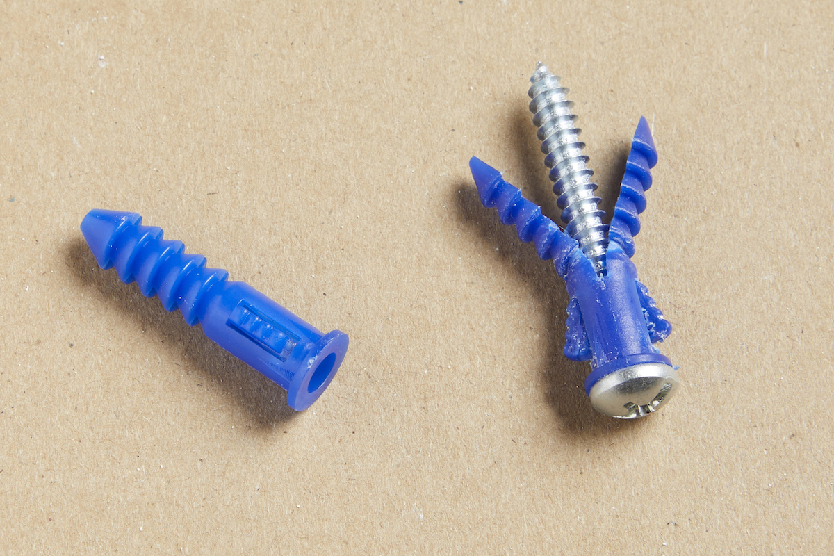 Two blue expansion drywall anchors against a brown background.