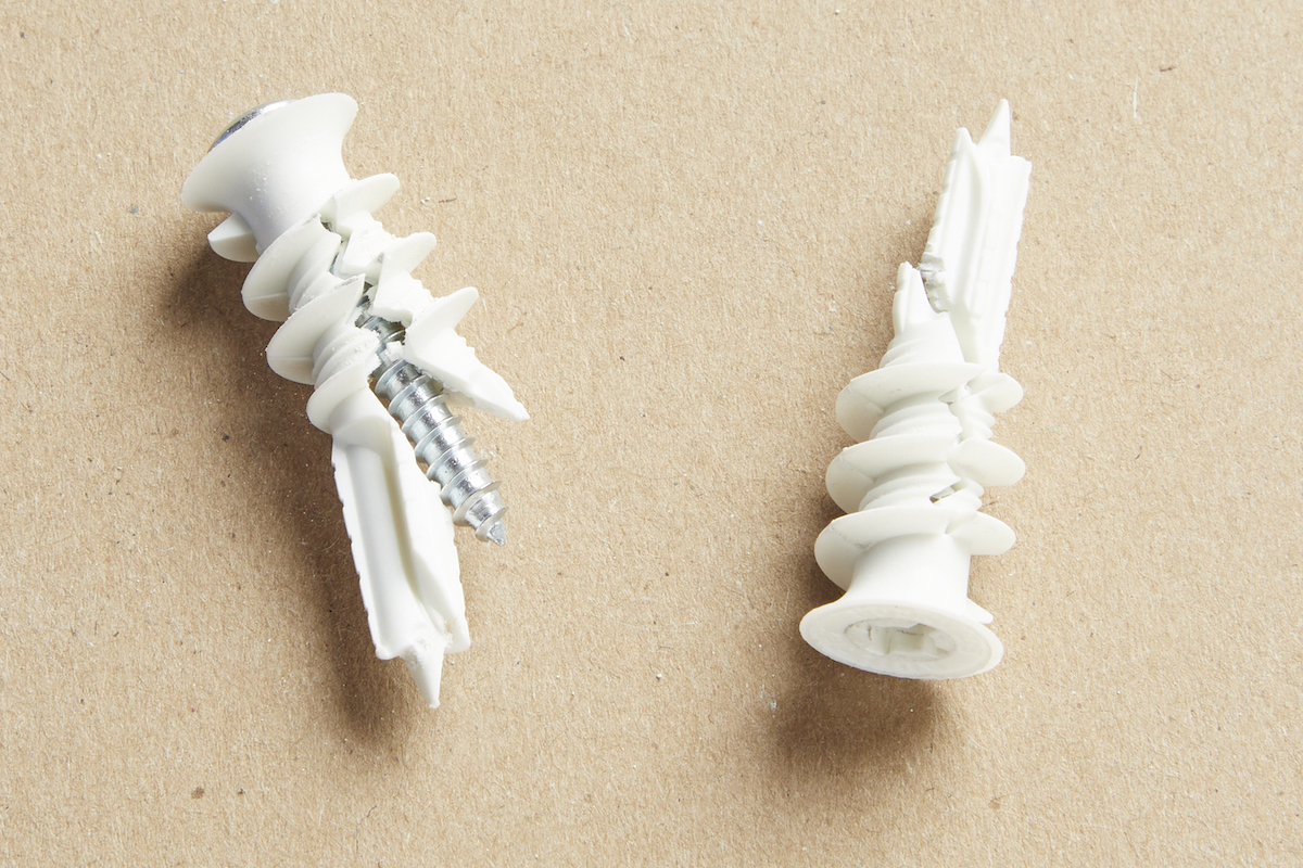 Two white threaded drywall anchors against a brown background.