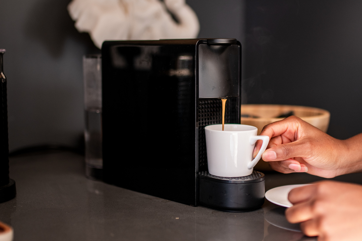 Black pod coffee maker dispensing into small coffee cup